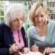 Female Neighbor Helping Senior Woman To Complete Form