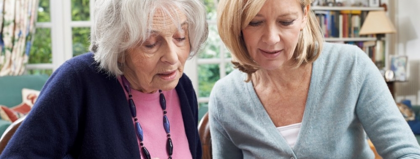 Female Neighbor Helping Senior Woman To Complete Form