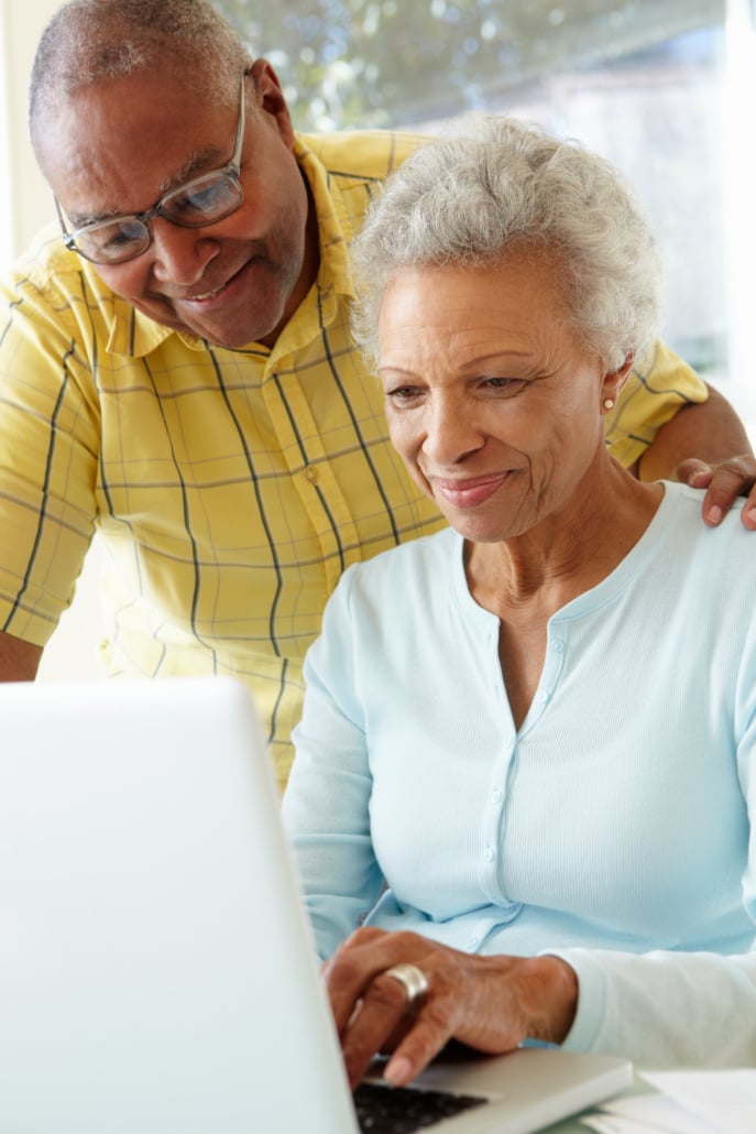 A smiling senior couple using a white laptop at home looking at mapt