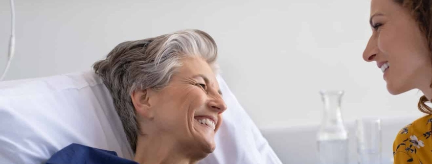 Woman and daughter smile at each other in hospital room