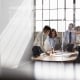 Four business colleagues stand talking in a meeting room