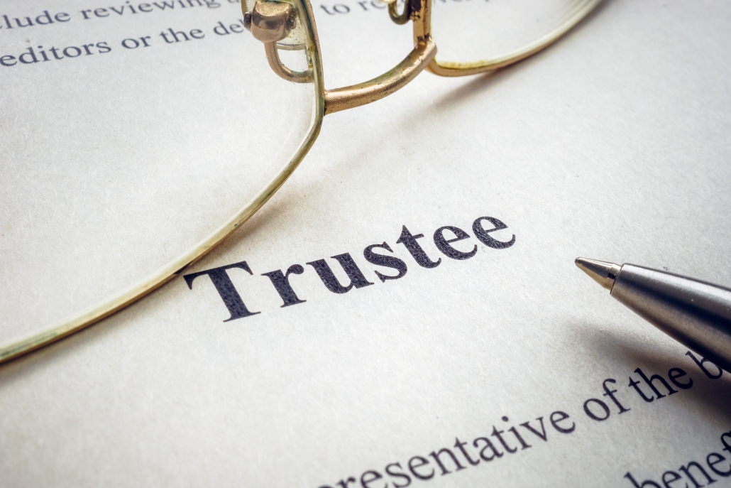 The word "Trustee" printed on a document with glasses laid atop it