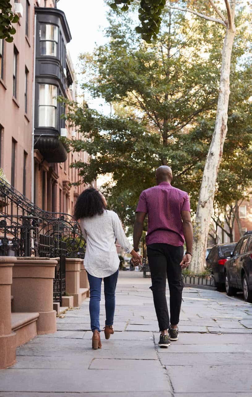 couple holding hands and walking through NYC